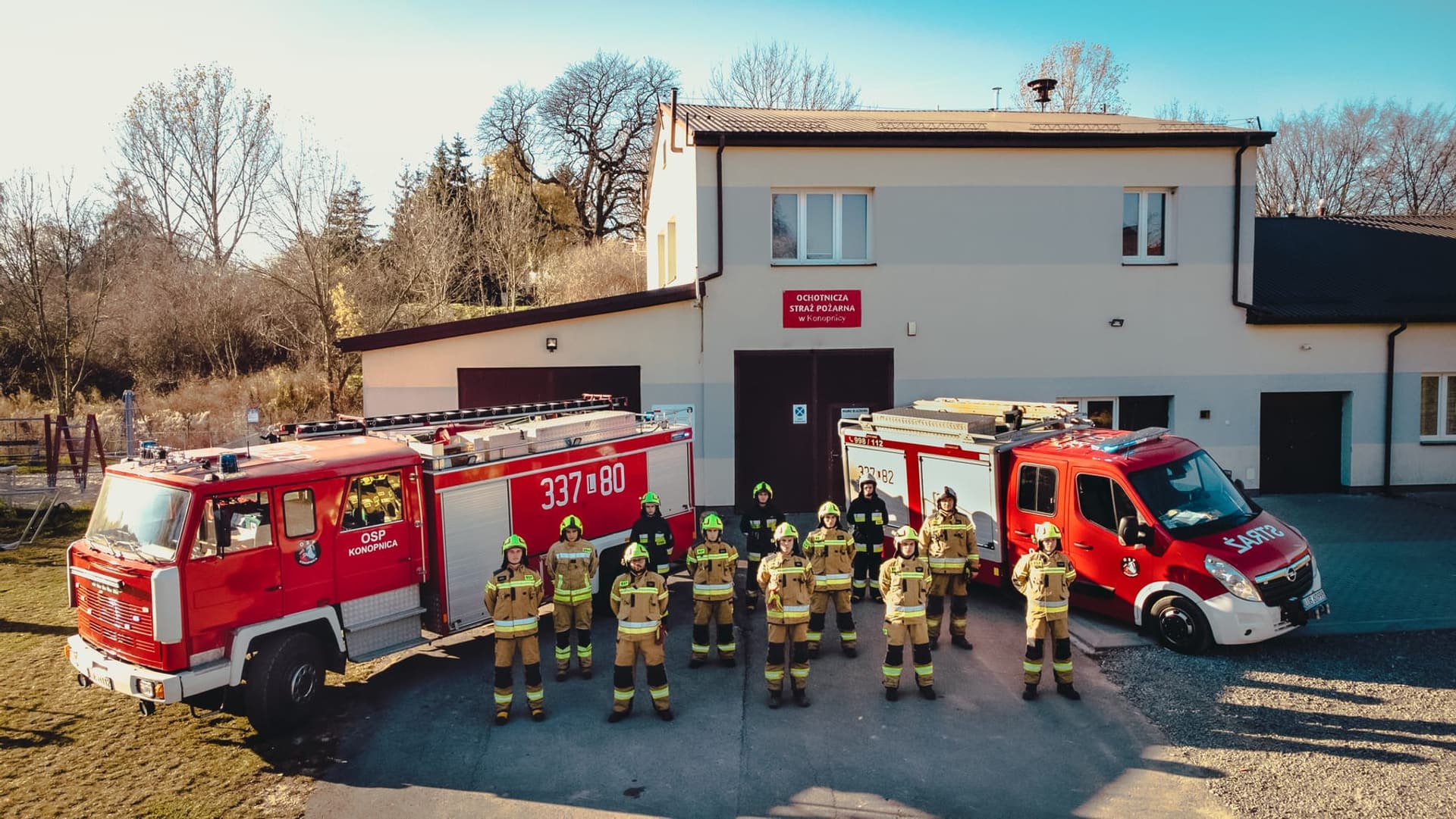 Strażacy OSP Konopnica przed remizą wraz z samochodami pożarniczymi